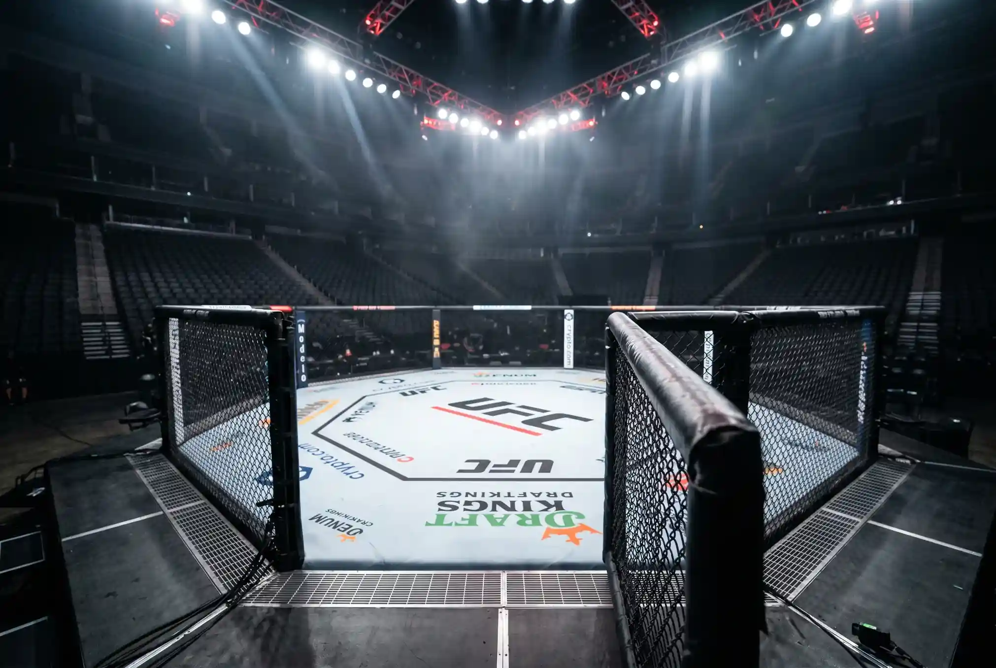 UFC octagon under bright arena lights with the cage in focus before a main card fight